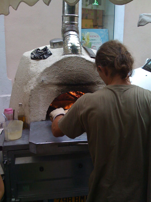 Cooking socca cakes in an oven at the Fayence market